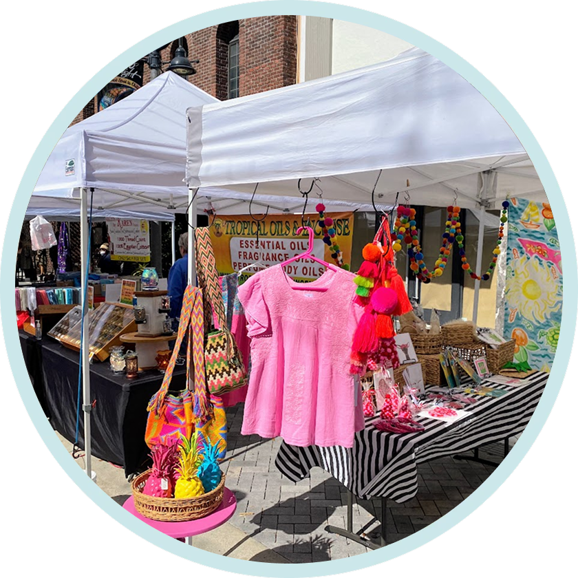 Market stall displaying pink dress and colorful accessories